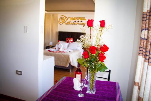 a table with a vase of roses and a bottle of wine at HOTEL KILLASUMAQ in Cajamarca