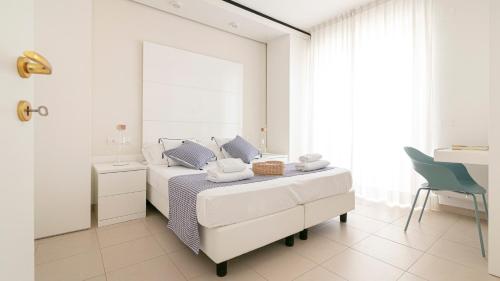 a white bedroom with a bed and a mirror at Residenza Excelsior - Bilocali Piano Terra in Marina di Montenero