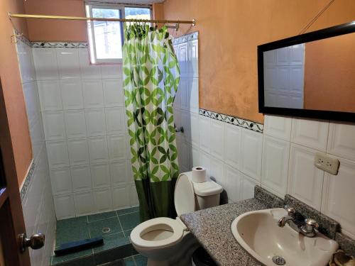 a bathroom with a toilet and a sink and a television at La Minga Hostal in Salinas