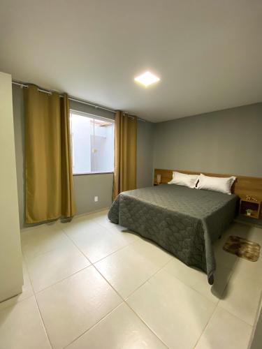 a bedroom with a bed and a large window at Acolhedor 2 quartos em ipiabas in Barra do Piraí