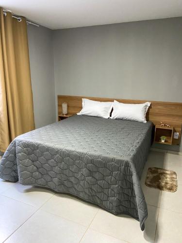 a bedroom with a bed with a gray comforter at Acolhedor 2 quartos em ipiabas in Barra do Piraí