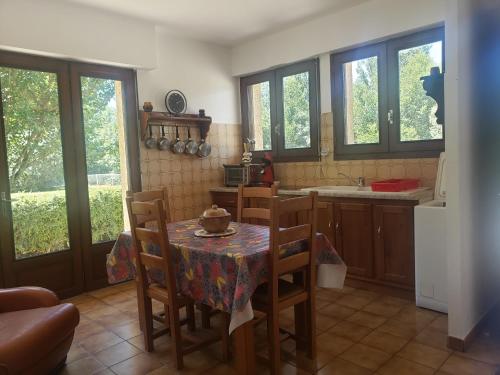 une cuisine avec une table, des chaises et des fenêtres dans l'établissement CHEMIN ROYAL AU BORD DU LOT, à Pierrefiche