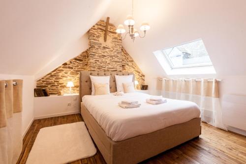a bedroom with a large bed with a stone wall at La Coquette - Tout confort - 100m du Canal - Calme - Wifi in Malestroit