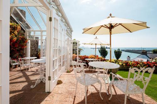 un patio con mesas, sillas y una sombrilla en Panorama Guest House en Saint Aubin