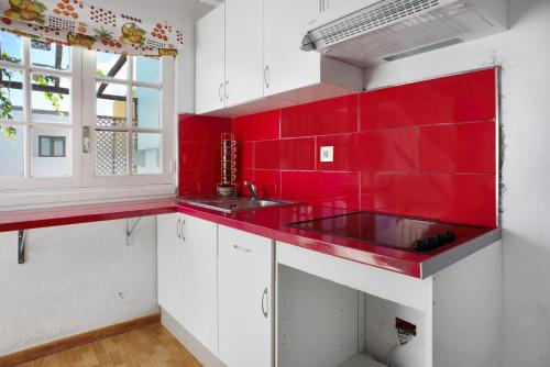 a red kitchen with white cabinets and a red wall at Playa del Hombre in Playa del Hombre