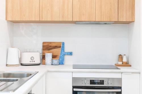 a kitchen with white cabinets and a stove top oven at 'Botanica Hoja' A Nightcliff Balcony Refresh in Darwin