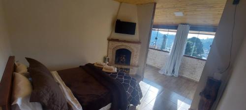 1 dormitorio con chimenea, 1 cama y TV en Recanto das Glicínias, en Monte Verde