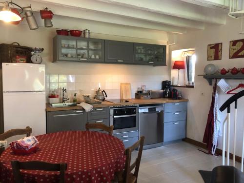 a small kitchen with a table and a refrigerator at Le Clos du Mont Jarry in Le Val-Saint-Père