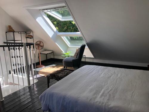 1 dormitorio en el ático con 1 cama y 1 silla en Le Clos du Mont Jarry, en Le Val-Saint-Père