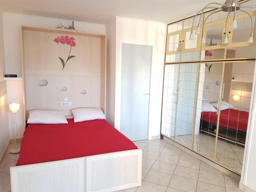 une chambre avec un lit rouge et un miroir dans l'établissement Appartement Village Naturiste Lucky Luke, au Cap d'Agde
