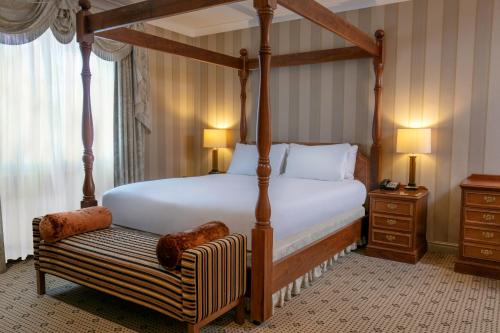 a bedroom with a four poster bed and a bench at Forest Pines Hotel, Spa & Golf Resort in Brigg