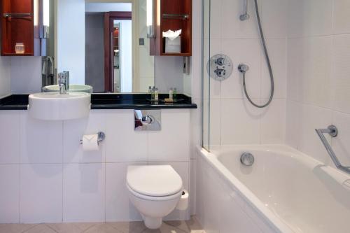 a bathroom with a toilet and a tub and a sink at Forest Pines Hotel, Spa & Golf Resort in Brigg