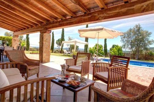a patio with chairs and a table with an umbrella at Can Lari Chalet in Vall-Llobrega