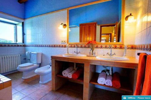 a bathroom with two sinks and a toilet and a mirror at Mas dels Avis Tipica Masia Catalana in Vall-Llobrega
