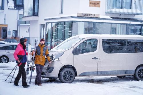 two people standing next to a white van in the snow at Rezort Maladinovo pri Liptovskej Mare in Liptovský Mikuláš