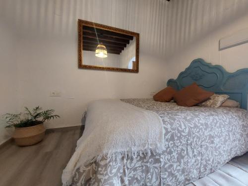 1 dormitorio con 1 cama con cabecero azul y espejo en Apartamento Bulería, en Jerez de la Frontera