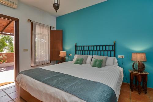 a bedroom with a large bed with a blue wall at Group Villa 14 Pool wifi Air in Frigiliana