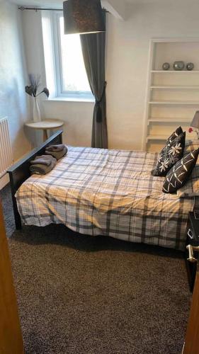 a bedroom with a bed with a plaid blanket and a window at Haworth Prime Location 3 Bedroom Duplex Apartment in Haworth