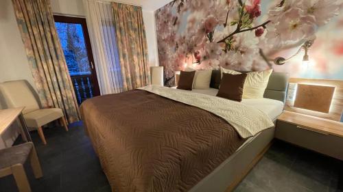 a bedroom with a large bed with a flower painting on the wall at Hotel Paidion in Braunlage