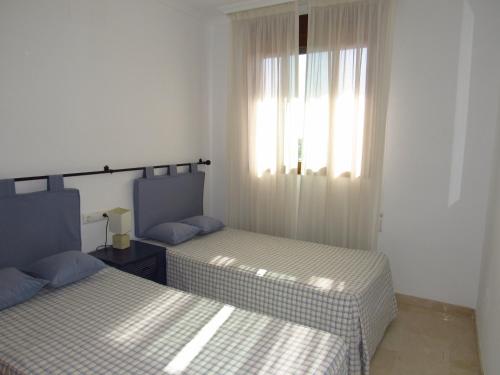 een slaapkamer met 2 bedden en een raam met gordijnen bij Penthouse Benalvistas Torregolf Seaview in Benalmádena