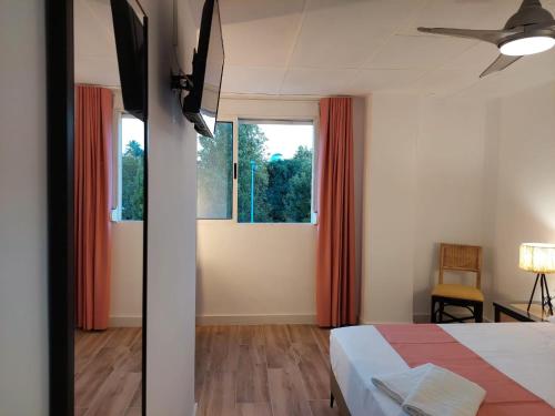 a bedroom with a bed and two windows with red curtains at Hostal GARDEN ROUS in Paiporta