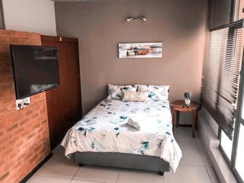a small bedroom with a bed and a television at City living near Nelson Mandela bridge in Johannesburg