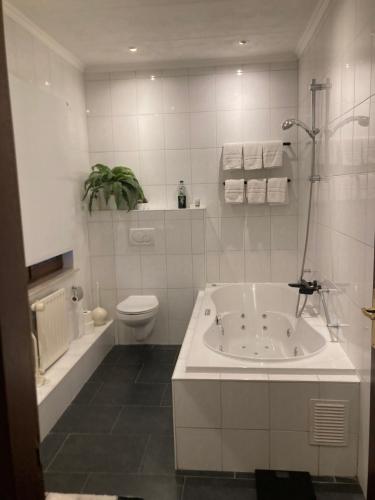 a white bathroom with a tub and a toilet at Hotel Rido in Valkenburg