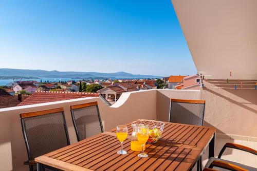 a wooden table with wine glasses on a balcony at Merita Apartments with Pool in Sveti Filip i Jakov