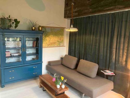 een woonkamer met een bank en een blauwe kast bij Appartement de Tuinkamer in Kampen