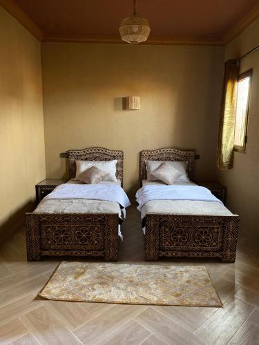 two beds sitting next to each other in a room at Sunny Place apartments in Merzouga