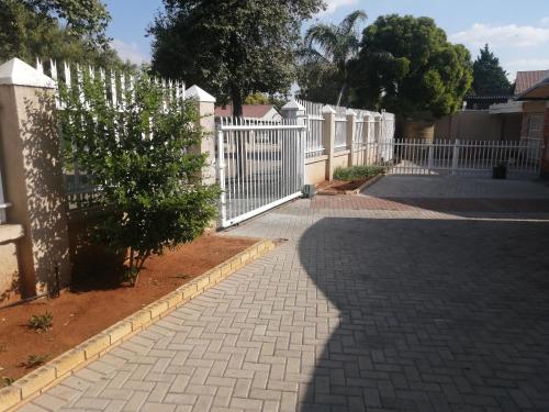 a white fence next to a brick walkway at Midway Overnight Rooms in Kimberley