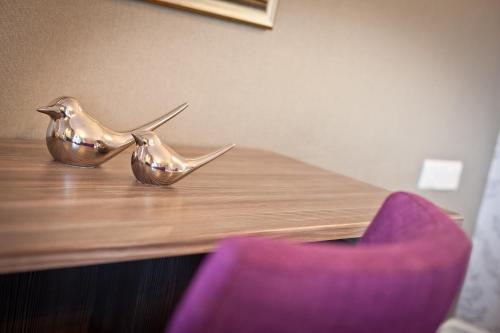 two metal birds sitting on top of a wooden table at Windermere Hillthwaite Hotel in Windermere