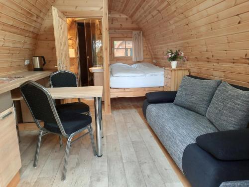 una sala de estar con sofá y mesa en una cabaña en 27 Premium Camping Pod en Silberstedt