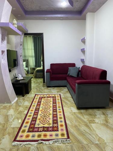 a living room with a red couch and a rug at Petra Rose Apartment in Wadi Musa