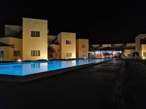 an empty swimming pool in front of a building at night at Chalet no paraíso in Maracajaú