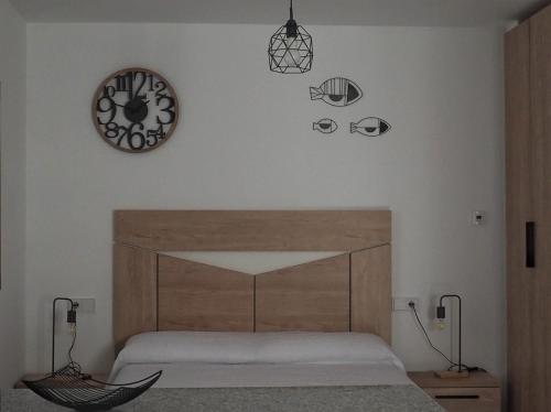 a bedroom with a bed and a clock on the wall at El APARTAMENTUCO in Pechón