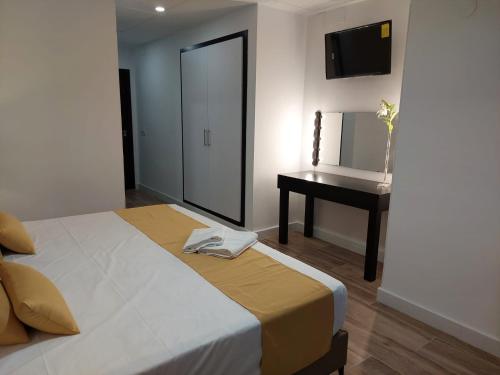 a bedroom with a bed and a table and a mirror at Hostal GARDEN ROUS in Paiporta