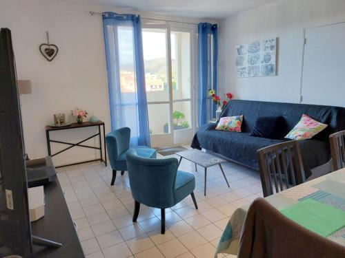 un salon avec un canapé bleu et des chaises dans l'établissement CAPET LES DAHLIAS - Axelle Loc'Appart, à Sainte-Maxime