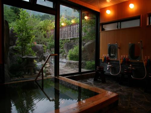 uma casa de banho com uma piscina de água e uma janela em Ryokan Kutsuroginoya Yuu em Takayama