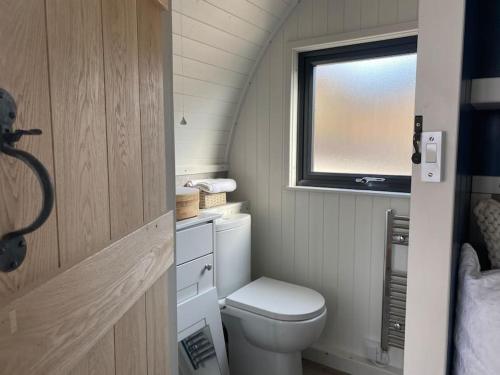 a small bathroom with a toilet and a window at Sunset Cabin- glass frontage luxury couples cabin. in Shieldaig
