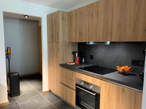 une cuisine avec des armoires en bois et un four à plaques de cuisson dans l'établissement Appartement 6 pers avec balcons, garage et local à ski - FR-1-198-238, à Châtel