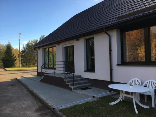 a house with a table and two chairs in front of it at Klykių apartamentai in Inkartai