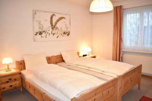 a bedroom with a large bed with white sheets at Lodola 298 3 Hk , Wohnung 3 in Lenzerheide