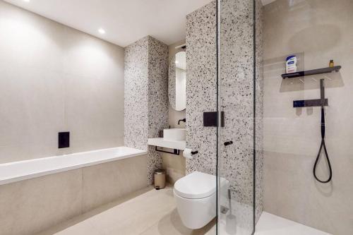 a bathroom with a toilet and a glass shower at Modern 1 bed flat with balcony in Kensal Green in London