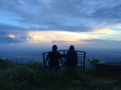 two people sitting on a bench watching the sunset at Swastika Homestay and Travels Kurseong Bazar Near HDFC Bank NH55 Road Kurseong in Kurseong