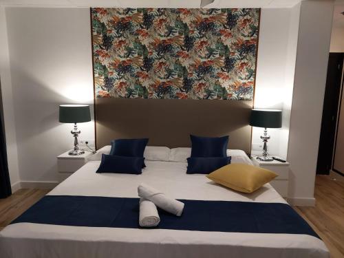 a bedroom with a large bed with blue and yellow pillows at Hostal GARDEN ROUS in Paiporta