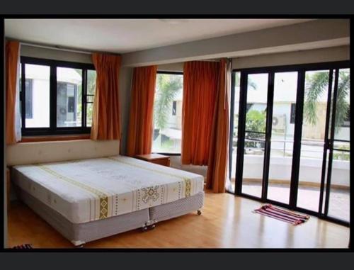 a bedroom with a large bed and large windows at บ้านนาวาภิรมย์ ชะอํา in Ban Khlong Khot