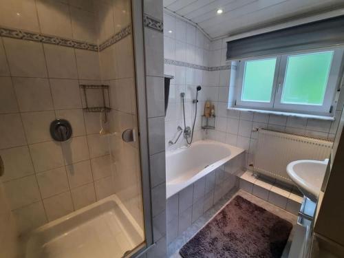 een badkamer met een douche, een bad en een wastafel bij Ferienwohnung Schwarzwaldblick in Bad Rippoldsau-Schapbach