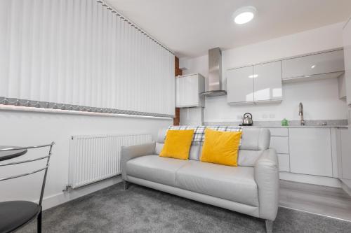 a white living room with a couch with yellow pillows at 1 Bed City Studio near Theatre and Station Secure Parking in Hull