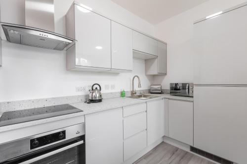 a white kitchen with white cabinets and stainless steel appliances at 1 Bed City Studio near Theatre and Station Secure Parking in Hull